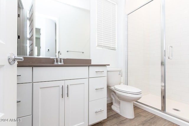 bathroom featuring toilet, a shower with door, vanity, and hardwood / wood-style flooring