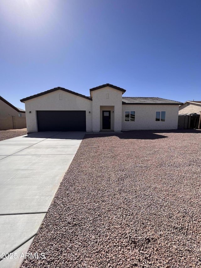 view of front of property featuring a garage, fence, concrete driveway, and stucco siding