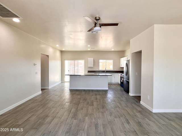 kitchen with dark countertops, visible vents, freestanding refrigerator, white cabinets, and wood finished floors