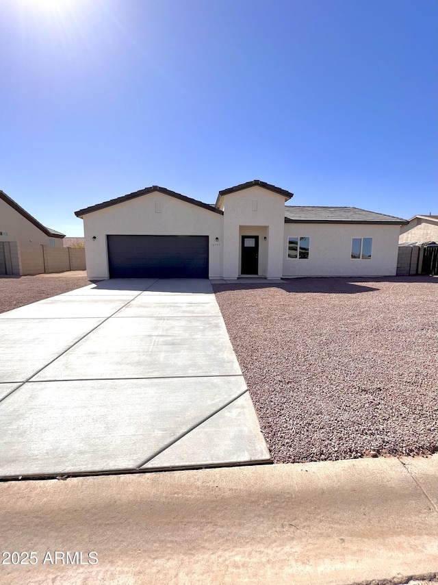 view of front facade with driveway, an attached garage, fence, and stucco siding