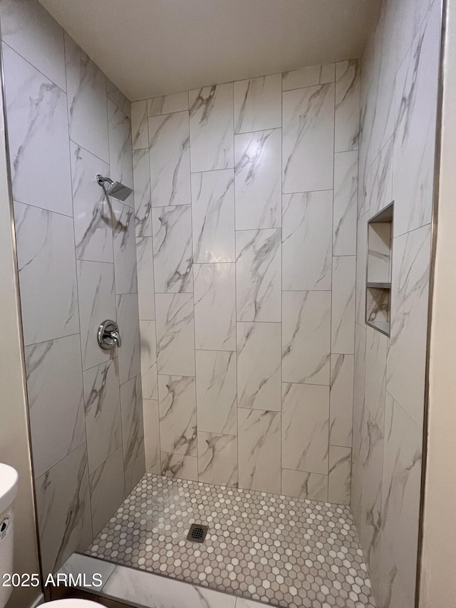 bathroom featuring a tile shower and toilet