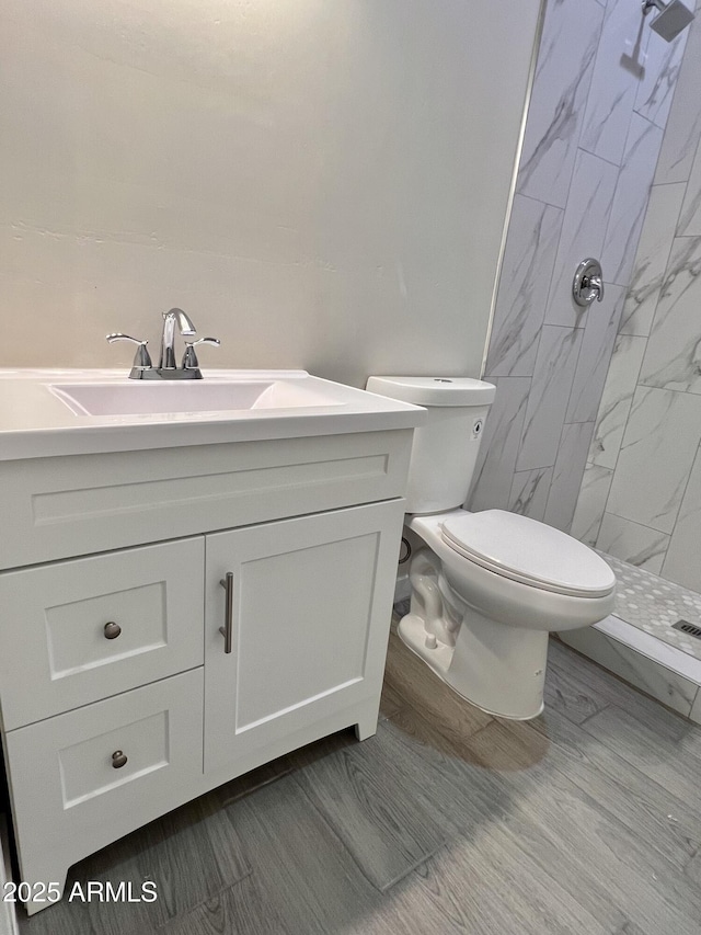 bathroom with toilet, a stall shower, and vanity