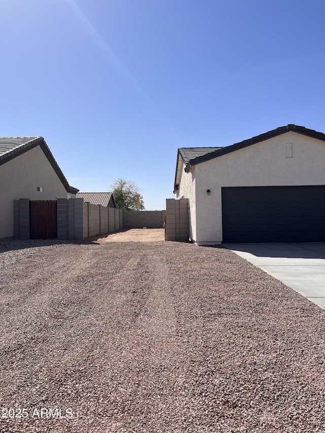 view of property exterior with driveway, fence, and stucco siding