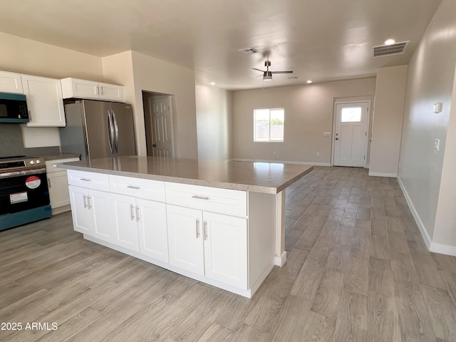 kitchen with stainless steel appliances, light wood-type flooring, visible vents, and white cabinetry