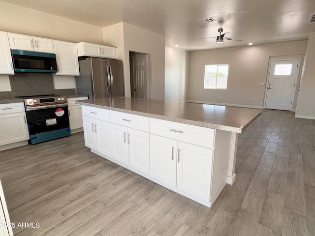 kitchen featuring visible vents, white cabinets, decorative backsplash, light wood-style flooring, and appliances with stainless steel finishes