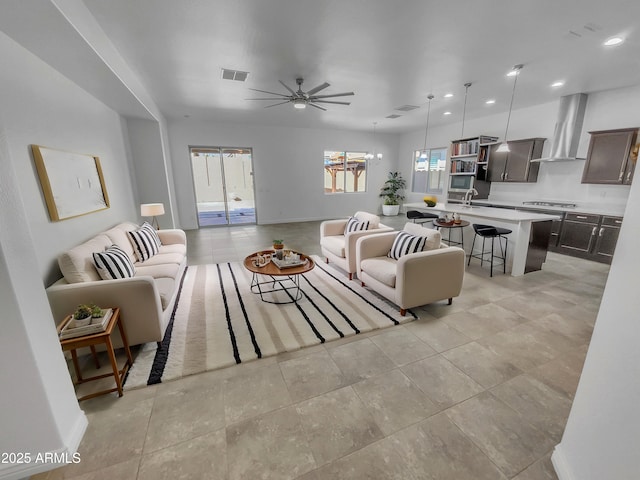 living area featuring visible vents, baseboards, light tile patterned flooring, recessed lighting, and ceiling fan with notable chandelier