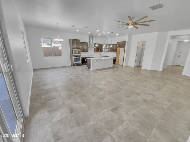 unfurnished living room featuring recessed lighting, ceiling fan with notable chandelier, visible vents, and baseboards