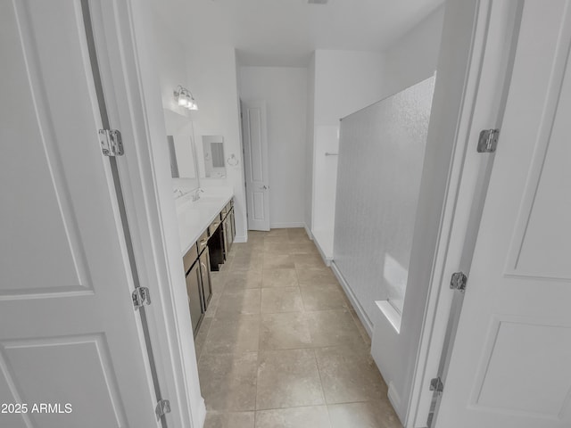 full bath featuring tile patterned floors, double vanity, baseboards, and a sink