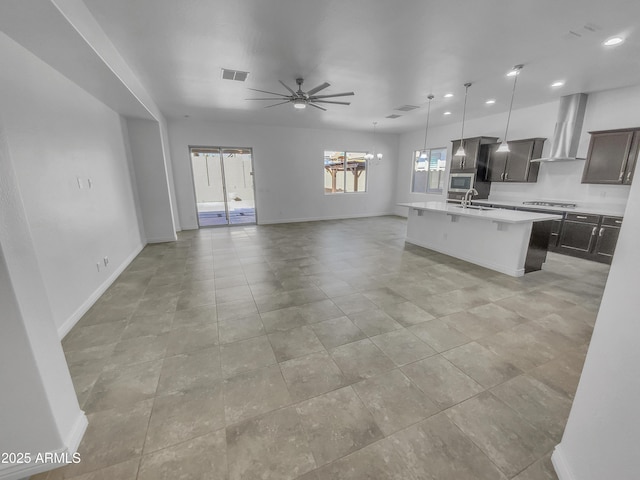 kitchen with light countertops, wall chimney range hood, open floor plan, and a sink