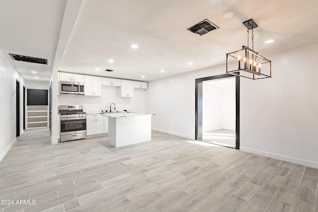 kitchen featuring sink, stainless steel appliances, light hardwood / wood-style flooring, pendant lighting, and white cabinets