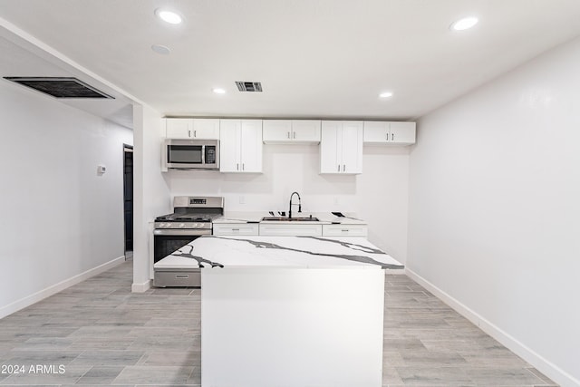 kitchen with sink, stainless steel appliances, light stone counters, light hardwood / wood-style flooring, and white cabinets