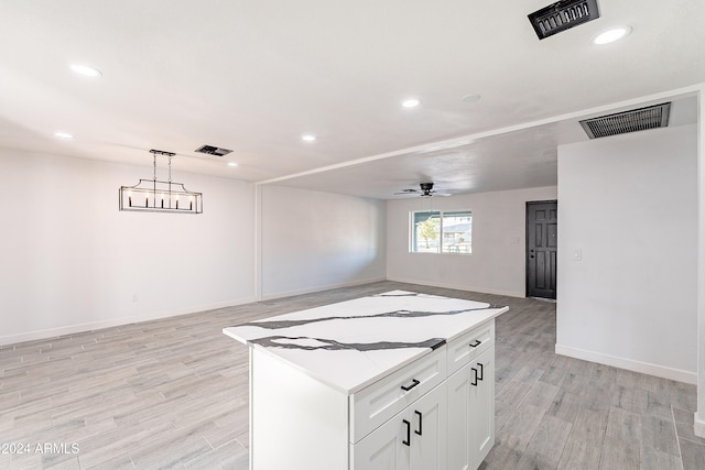 kitchen with ceiling fan, hanging light fixtures, a kitchen island, light hardwood / wood-style floors, and white cabinets