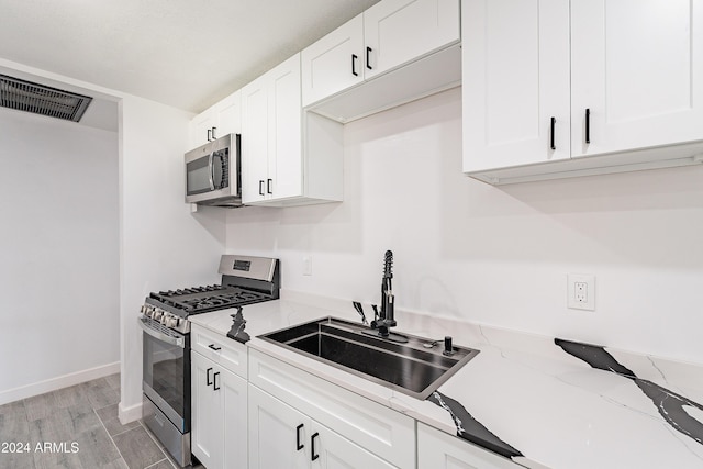 kitchen featuring light stone countertops, sink, white cabinets, and stainless steel appliances