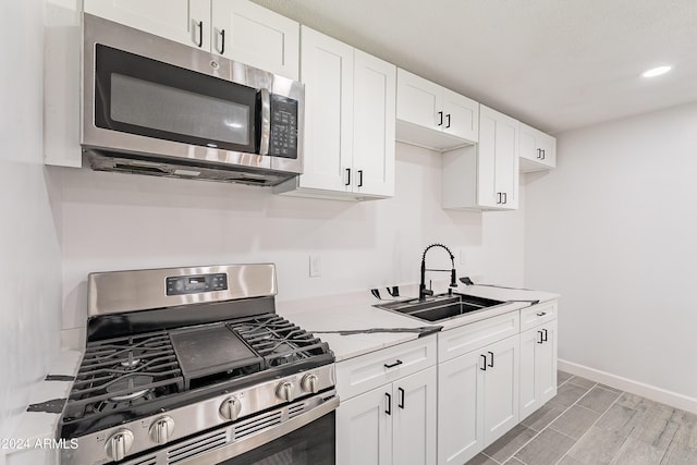 kitchen featuring white cabinets, stainless steel appliances, light hardwood / wood-style floors, and sink