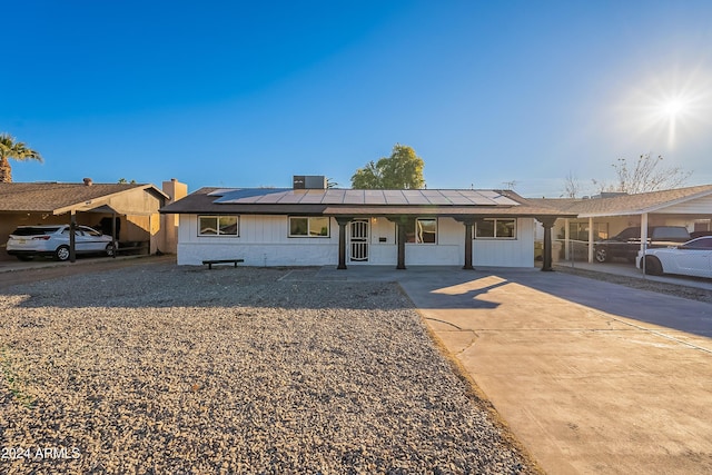 ranch-style home with solar panels and central air condition unit