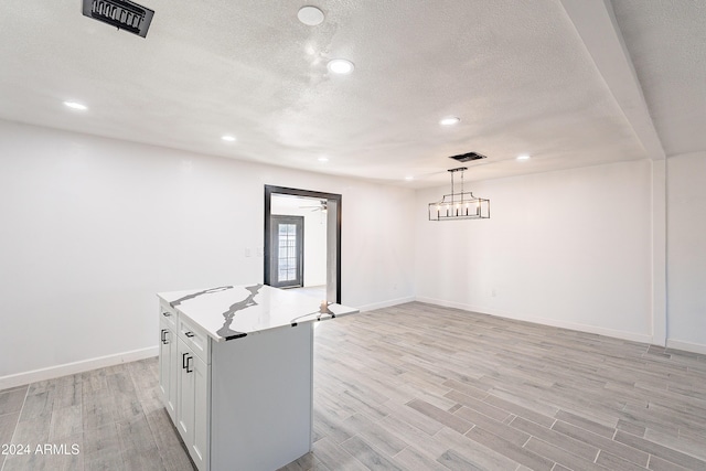 kitchen with white cabinetry, a kitchen island, light hardwood / wood-style floors, and decorative light fixtures