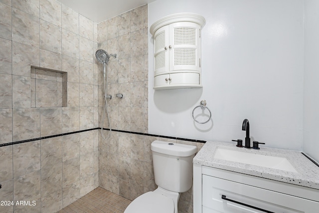 bathroom featuring tiled shower, vanity, and toilet