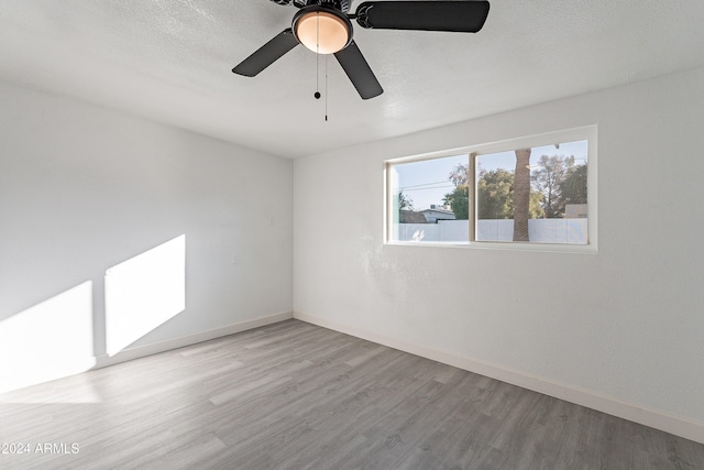 empty room featuring ceiling fan, light wood-type flooring, and a textured ceiling