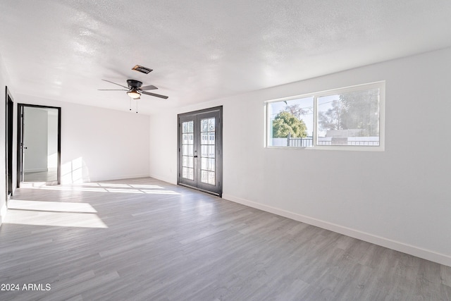 spare room featuring a textured ceiling, ceiling fan, light hardwood / wood-style flooring, and french doors