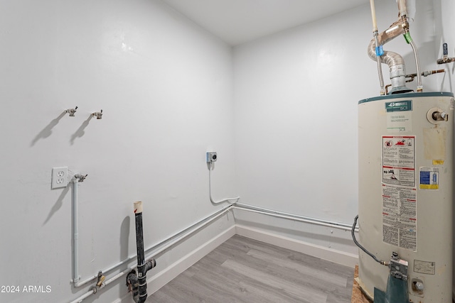 washroom featuring electric dryer hookup, water heater, and light hardwood / wood-style floors