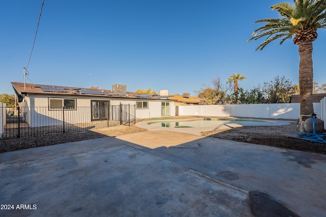 rear view of house featuring solar panels, a patio, and an empty pool