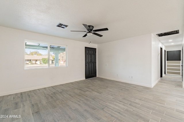 unfurnished room with ceiling fan, a textured ceiling, and light wood-type flooring