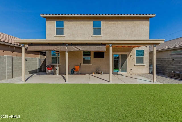 rear view of property featuring a lawn, a patio area, fence, and stucco siding