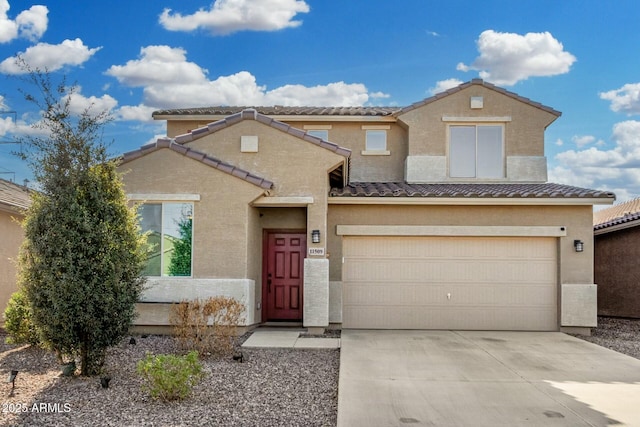 view of front facade with driveway, an attached garage, a tile roof, and stucco siding