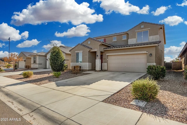 view of front of home featuring an attached garage, fence, a tile roof, driveway, and stucco siding