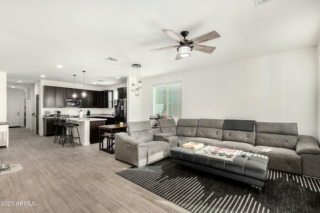 living area featuring a ceiling fan, recessed lighting, visible vents, and light wood finished floors