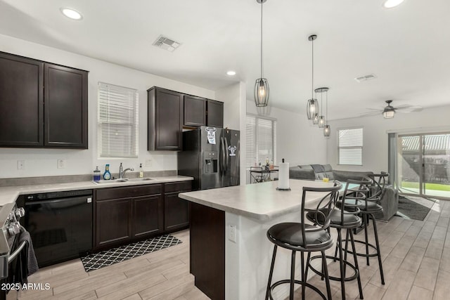 kitchen featuring dark brown cabinetry, visible vents, a kitchen breakfast bar, open floor plan, and appliances with stainless steel finishes