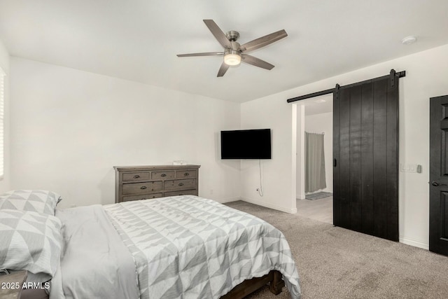 carpeted bedroom with a barn door, baseboards, and ceiling fan