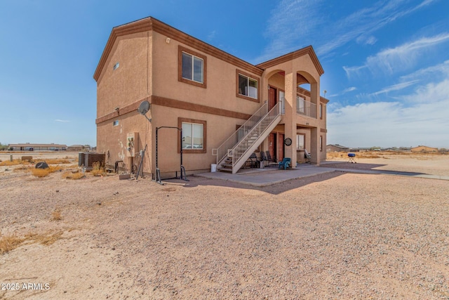 back of property featuring stairway, central air condition unit, stucco siding, and a patio area