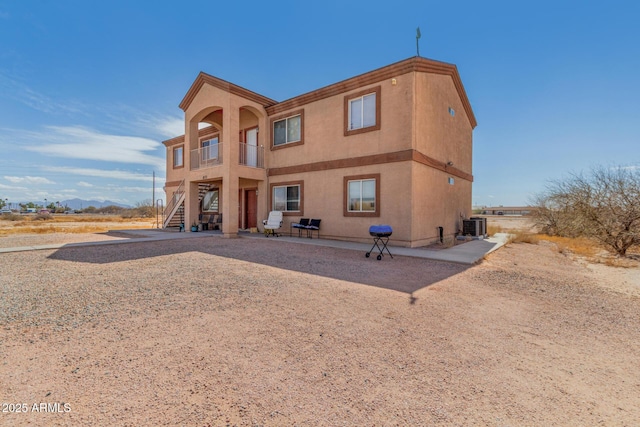 rear view of house with stairs, a patio, central AC unit, and stucco siding