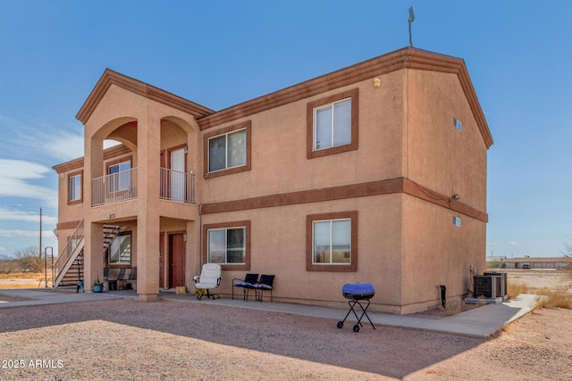 exterior space featuring stairway, a patio area, central AC, and stucco siding