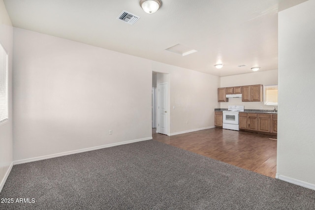 unfurnished living room with visible vents, dark carpet, dark wood-type flooring, and baseboards