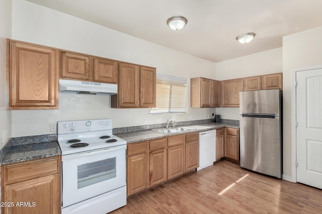 kitchen featuring light wood finished floors, under cabinet range hood, brown cabinetry, white appliances, and a sink