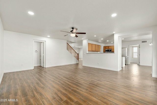 unfurnished living room with dark hardwood / wood-style flooring and ceiling fan