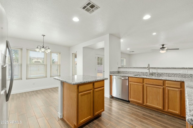 kitchen with ceiling fan with notable chandelier, hanging light fixtures, sink, light stone countertops, and appliances with stainless steel finishes