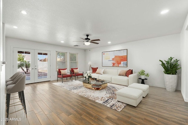 living room with french doors, a textured ceiling, ceiling fan, and hardwood / wood-style floors