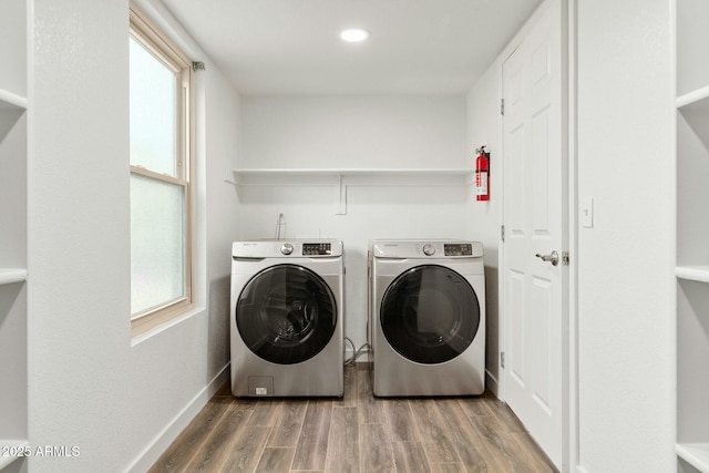 clothes washing area with hardwood / wood-style flooring, plenty of natural light, and washing machine and clothes dryer