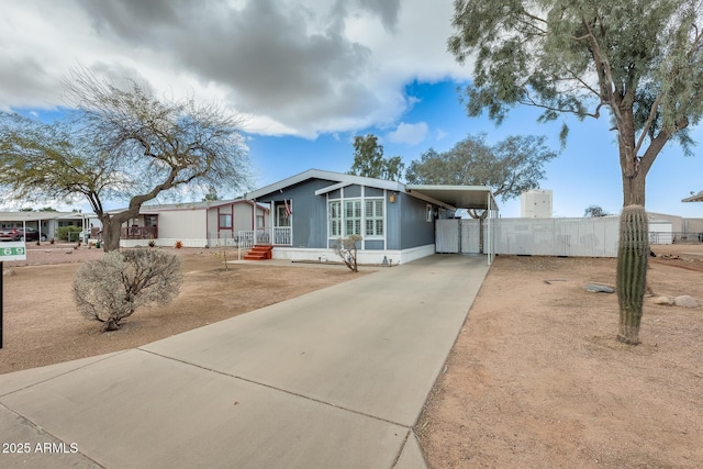 view of front of house with concrete driveway, a carport, and fence