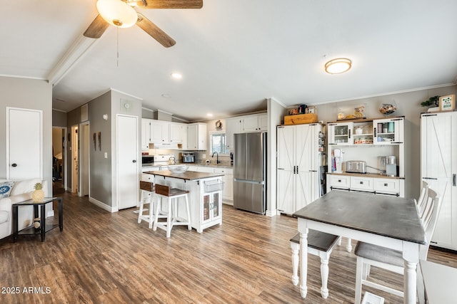 kitchen with lofted ceiling, dark wood-style floors, freestanding refrigerator, white cabinetry, and a sink