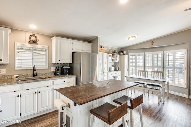 kitchen featuring dark wood finished floors, freestanding refrigerator, white cabinetry, vaulted ceiling, and a sink