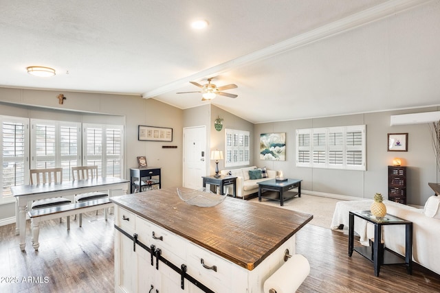 kitchen featuring vaulted ceiling with beams, a wall mounted AC, open floor plan, ceiling fan, and wood finished floors