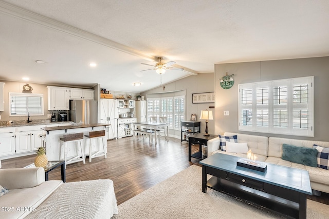 living area with dark wood-style flooring, vaulted ceiling with beams, and ceiling fan