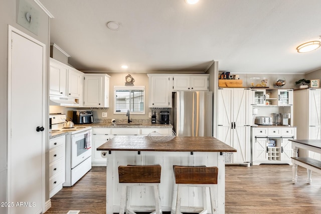 kitchen featuring white electric range, freestanding refrigerator, white cabinetry, a sink, and under cabinet range hood