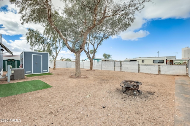 view of yard with a fire pit, an outbuilding, fence, a storage unit, and central air condition unit