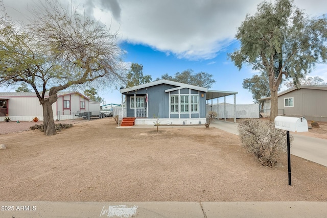 view of front facade featuring driveway, fence, and a carport