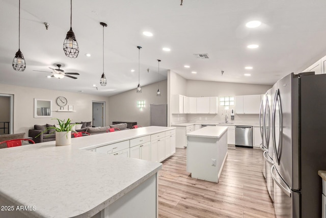 kitchen featuring appliances with stainless steel finishes, a spacious island, lofted ceiling, open floor plan, and a sink